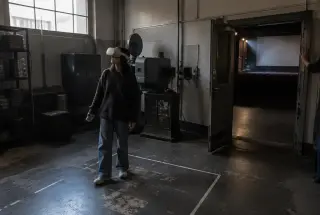 Visitor wearing a VR headset between a projection room and an empty cinema auditorium